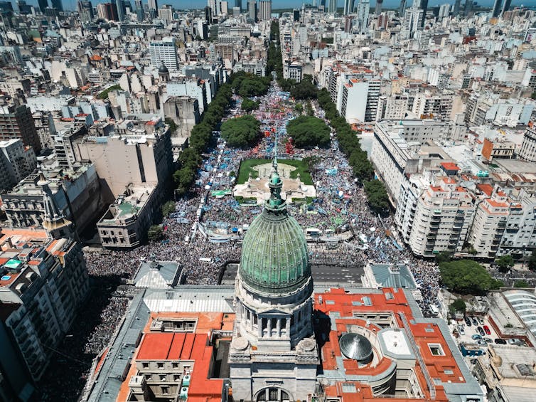 Aerial picture showing people gathering to protest in a large city square.