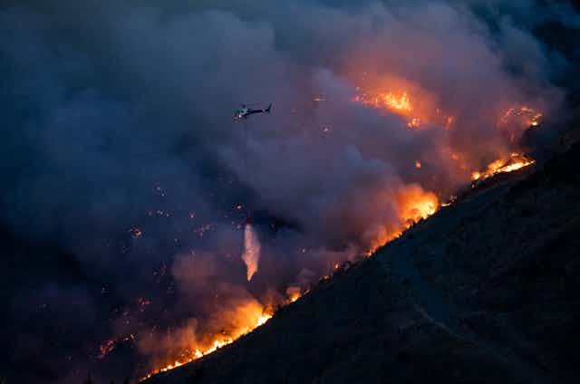 hillside on fire with helicopter above