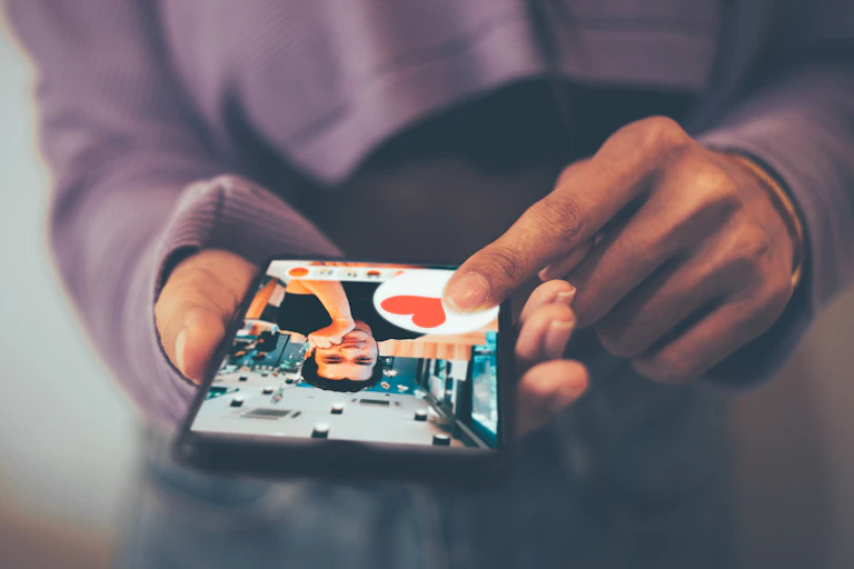 A person holding smartphone and swiping a heart on a smiling man's photo