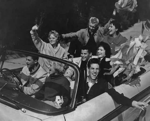 A group of teens in a convertible in the 1950s