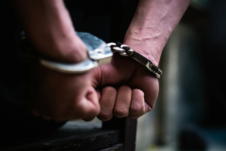 Close up photo of a man's hands in handcuffs behind his back
