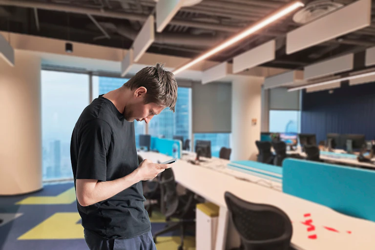 A man slouches while looking down at his phone.