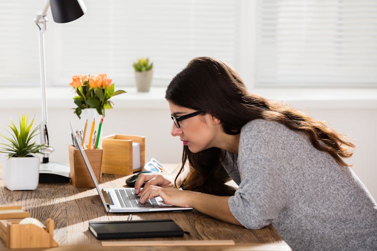 A woman slouches while using her laptop.