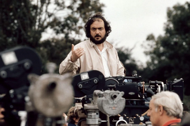 A bearded man (Stanley Kubrick) standing in front of a bank of film cameras talking to his crew.