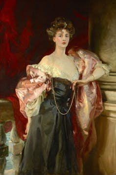 A lady in a black dress with a flowing pink cape.