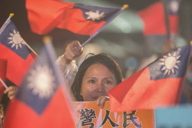 A woman at a campaign rally surrounded by flags of Taiwan.