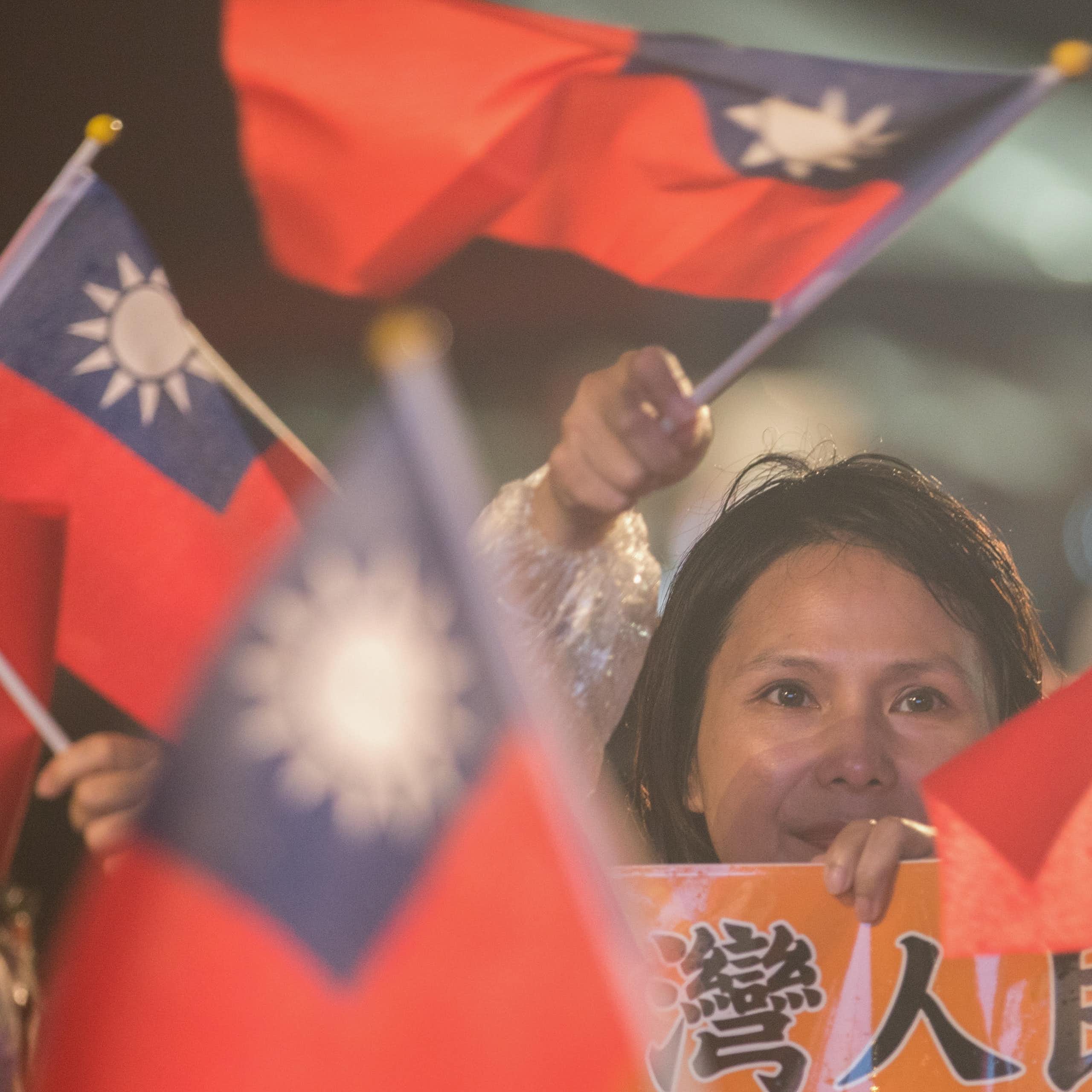 A woman at a campaign rally surrounded by flags of Taiwan.