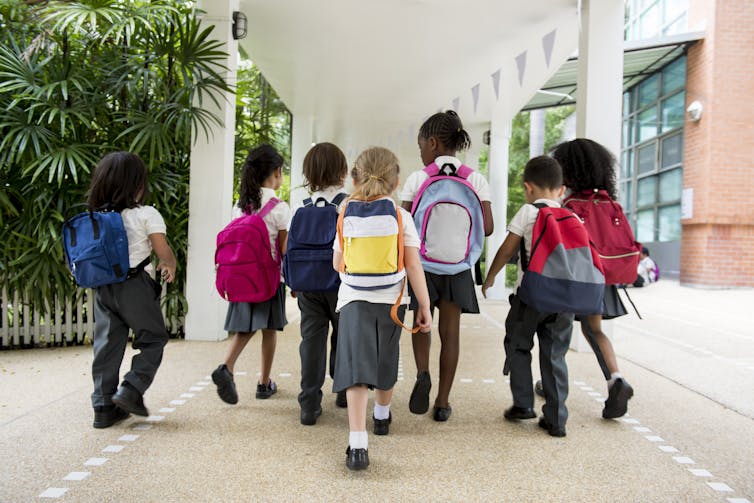 Young elementary school students in uniform walking away from the camera