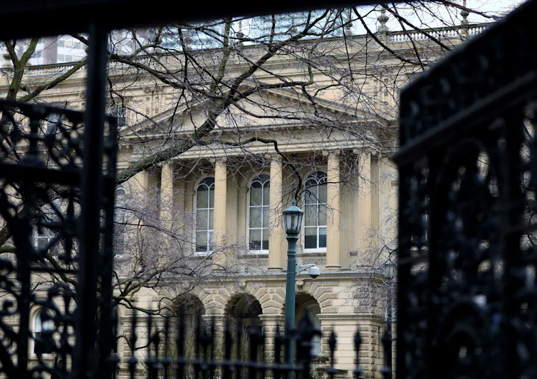 A large beige building behind a black gate