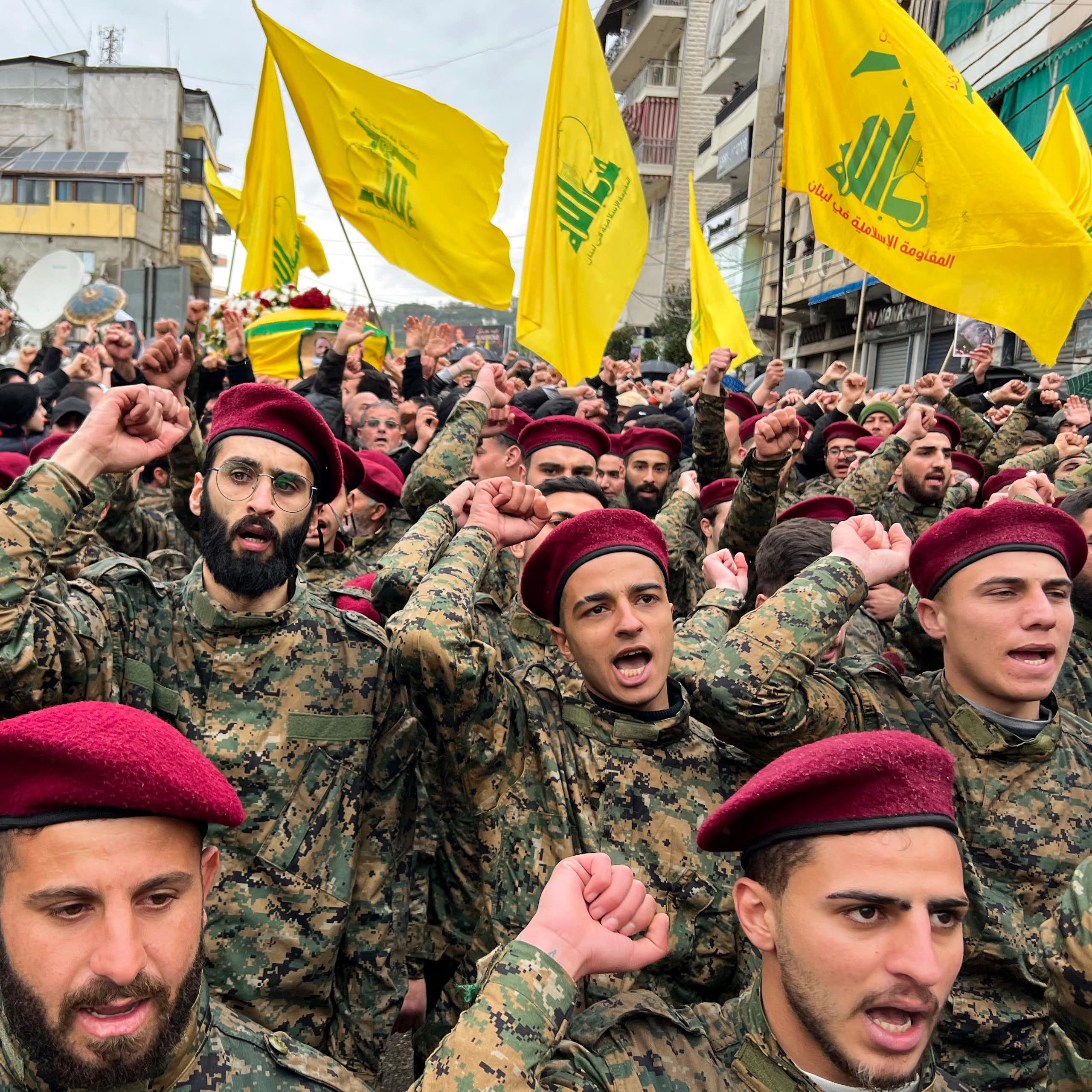 Hommes en uniforme et béret rouge avec des drapeaux du Hezbollah