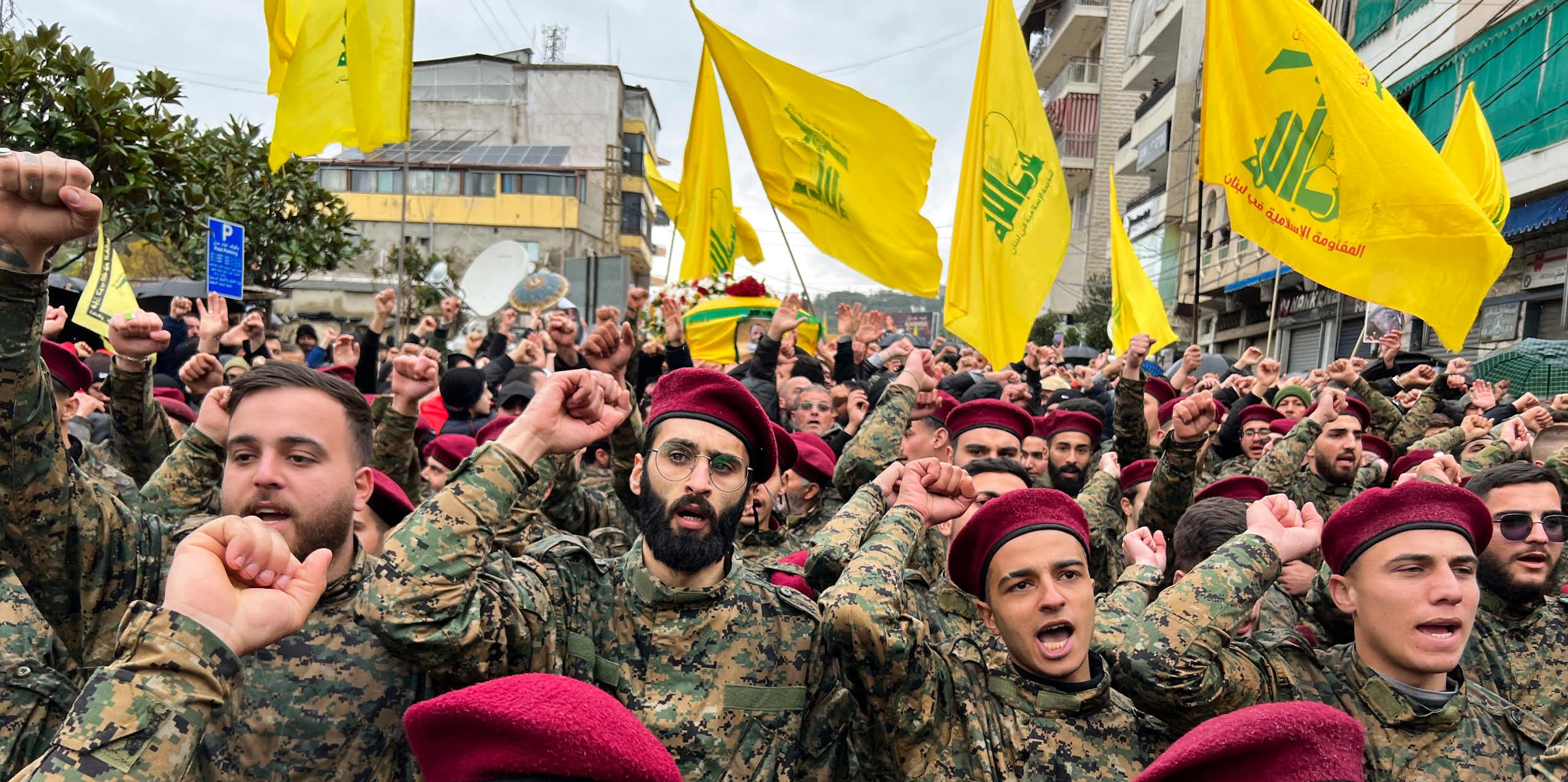 Hommes en uniforme et béret rouge avec des drapeaux du Hezbollah