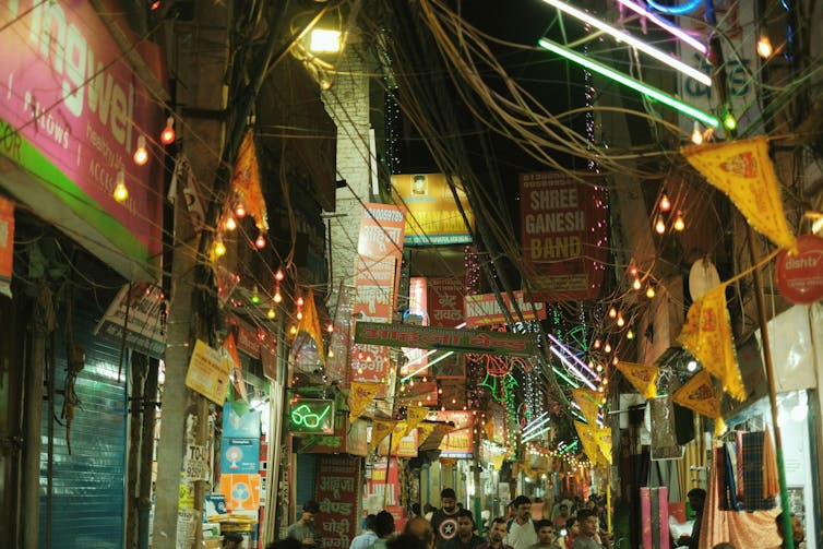 Delhi’s electronic bazaars are one of the city’s last non-elite commercial spaces 2 A market street with signs and lights at night.