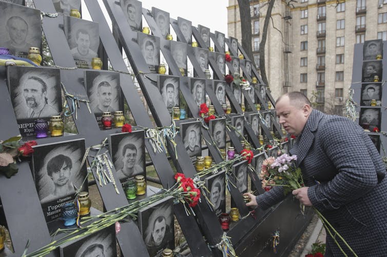 A man looks at pictures of people in a memorial to the Euromaidan protests of 2014 in Kyiv.