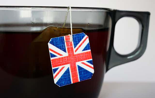 Close-up shot of a big cup of tea brewing with a tea bag featuring an english flag tag.