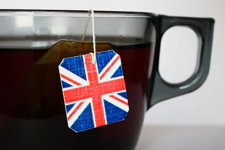 Close-up shot of a big cup of tea brewing with a tea bag featuring an english flag tag.