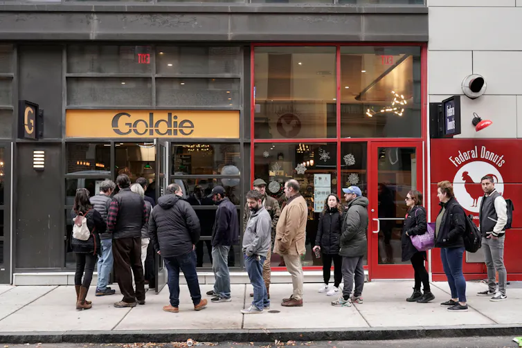 People queue in front of a restaurant.