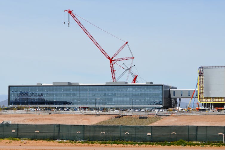 A large glass building under construction in a desert.