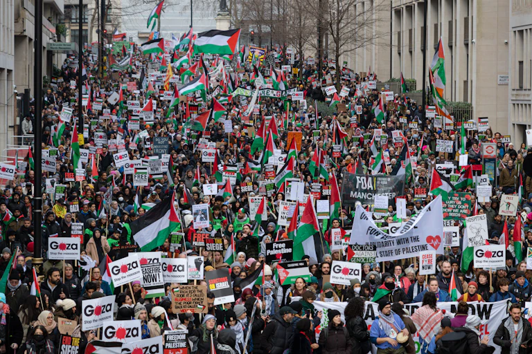 A large crowd of protesters carrying Palestinian flags fill a London street
