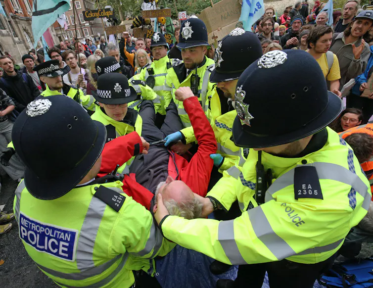 Police officers carrying a man they have arrested during an Extinction Rebellion protest