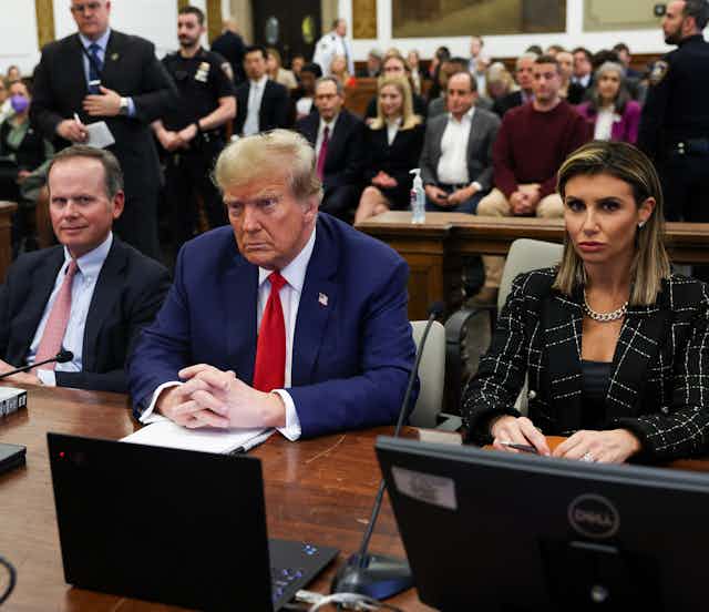 Three people in business clothes sit at a table.