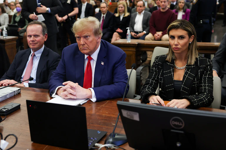 Three people in business clothes sit at a table.