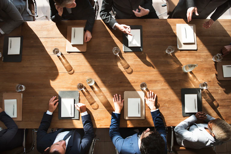 An overhead view of a people sitting and having a conversation around a conference table