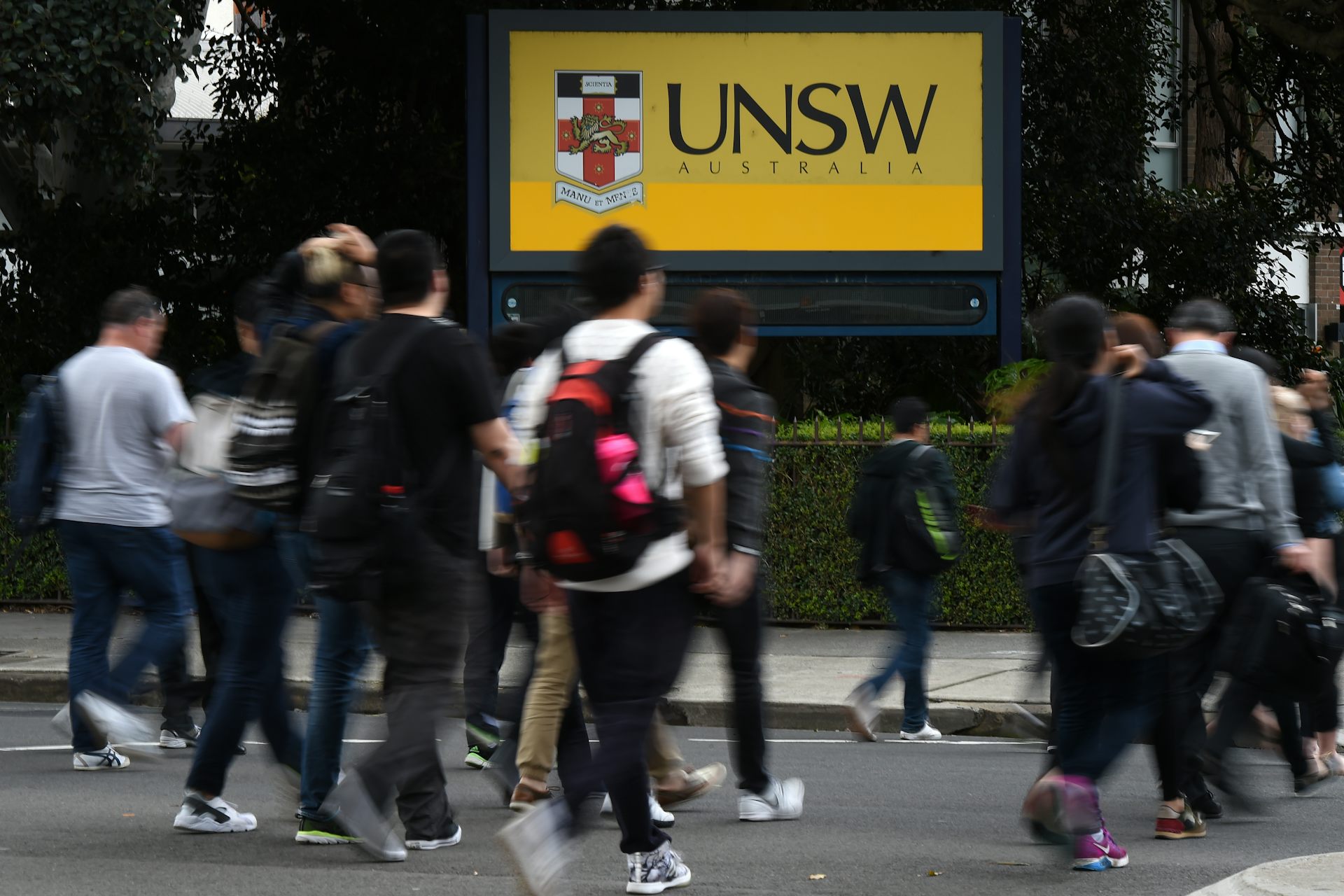 People cross the road outside an entrance to the University of New South Wales.