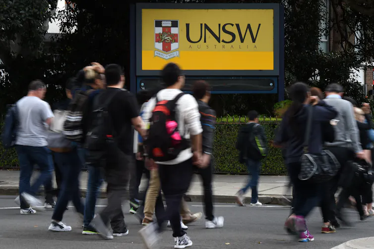 People cross the road outside an entrance to the University of New South Wales.