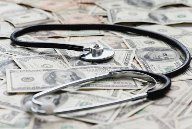 A stethoscope rests on a pile of $100 bills.