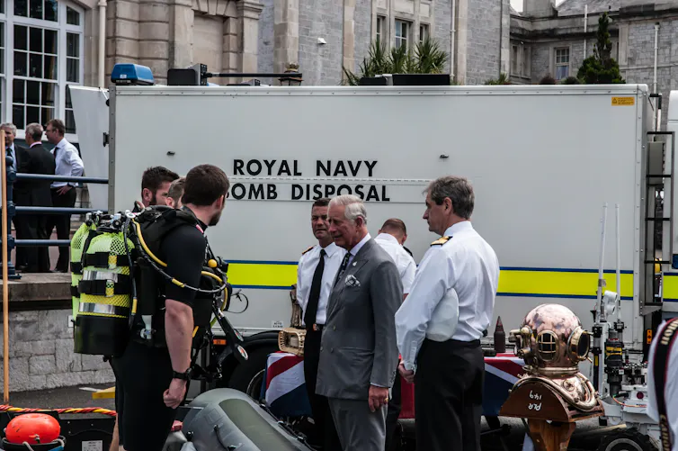 Men stand in front of an emergency vehicle with the then Prince of Wales.
