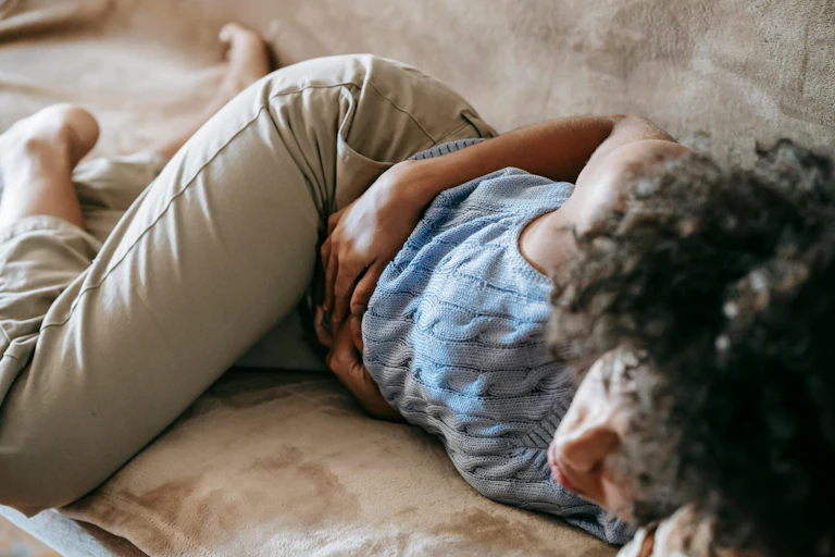 woman lies on couch with sore stomach