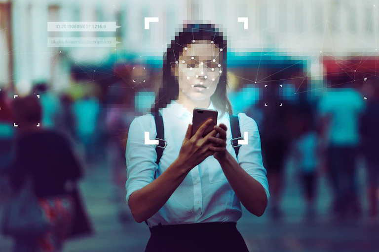 A woman with a pixelated face standing in a crowd using a smartphone