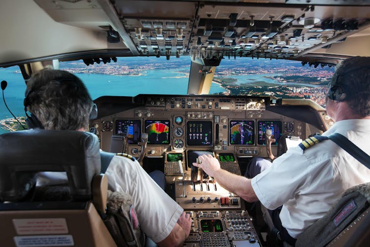 A photo of two pilots in a plane cockpit.