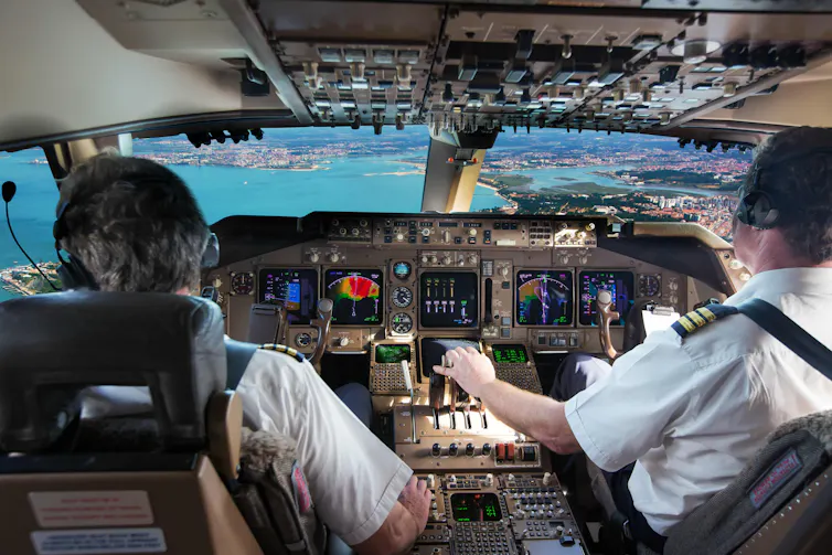 A photo of two pilots in a plane cockpit.