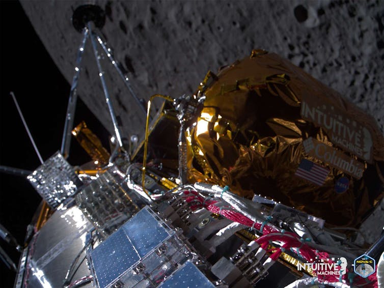 Close-up view of a machine with golden foil and various panels with a grey moon surface in the background