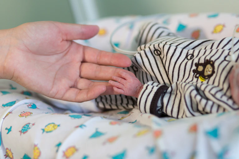 Mère tenant la main d'un bébé prématuré
