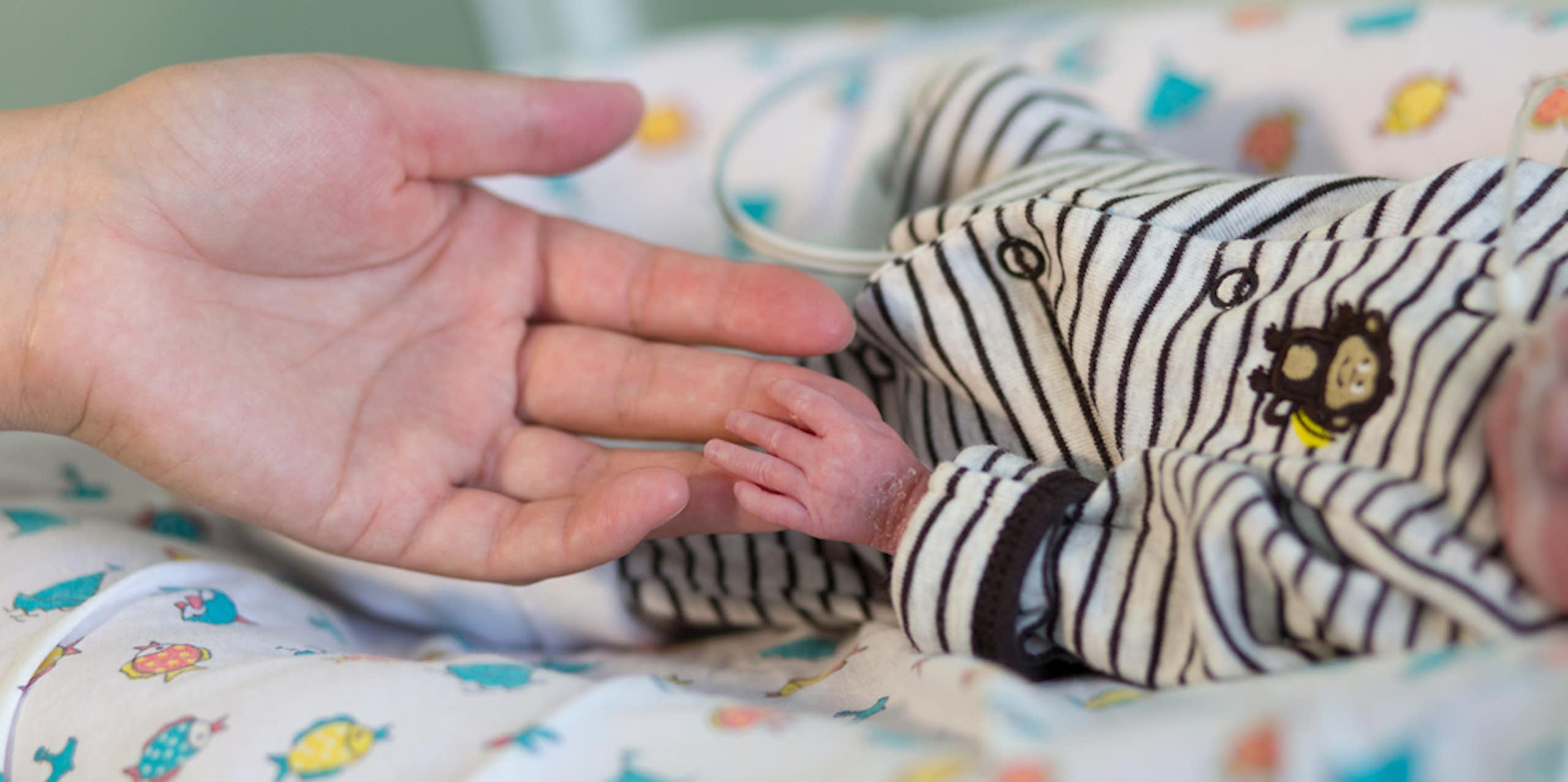 Mère tenant la main d'un bébé prématuré