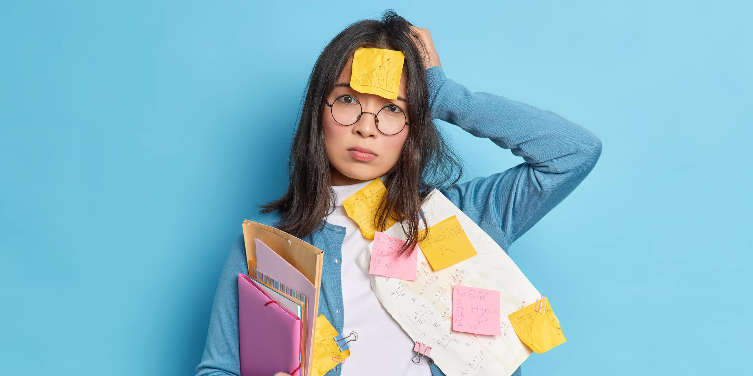 Forgetful woman covered in post-it notes and papers.