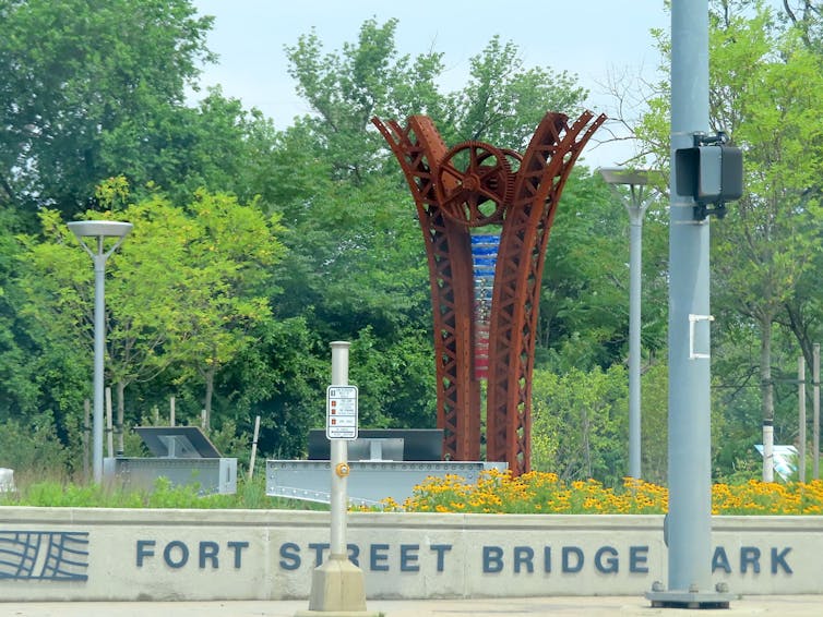 An iron sculpture commemorates industry and sits as the centerpiece of the Ford Street Bridge Park.