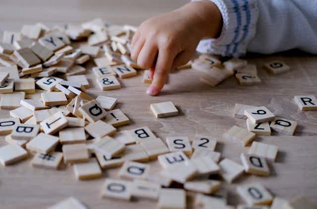 Un petit enfant de 3 ans joue des lettres en bois