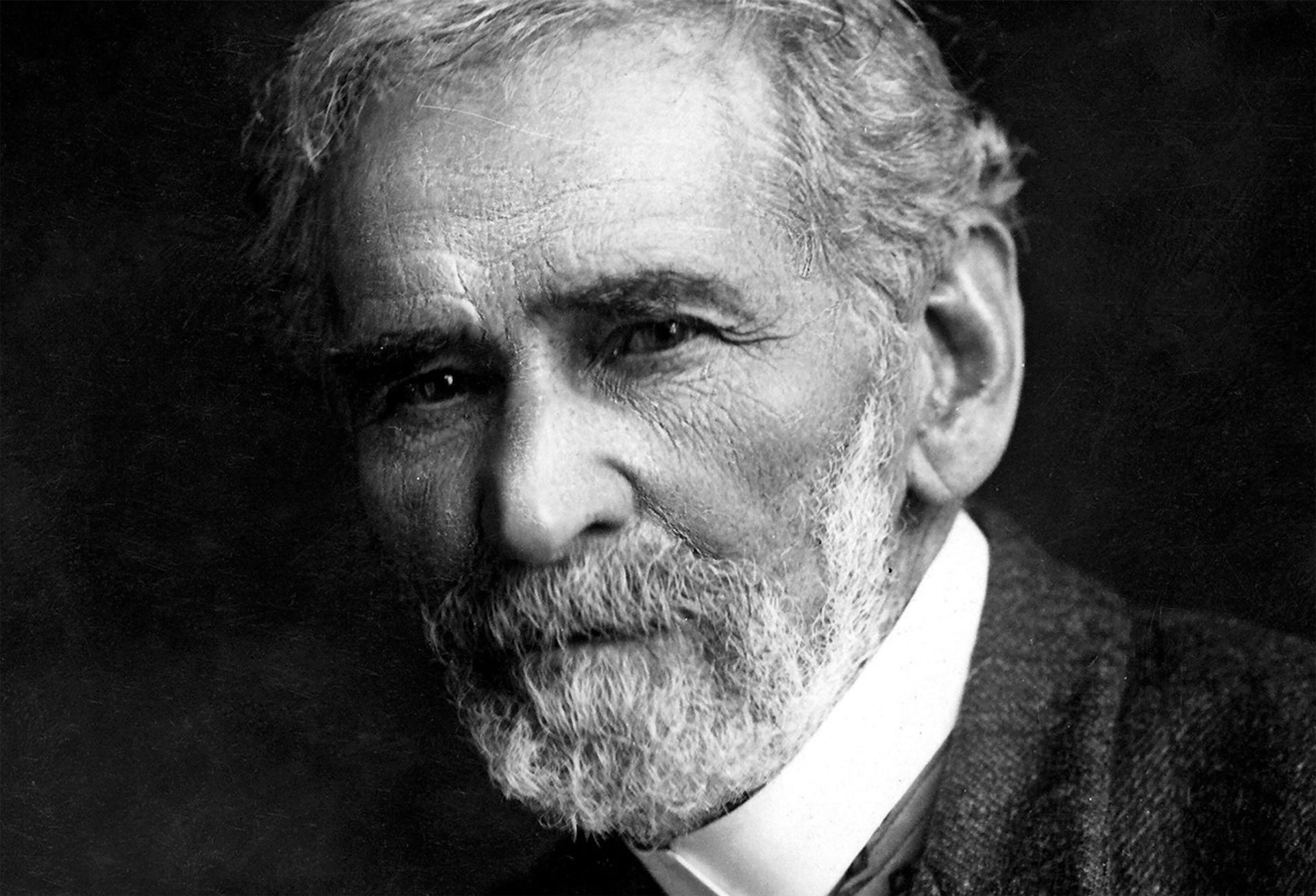 An older man with grey and a grey beard dressed in Victorian garb.