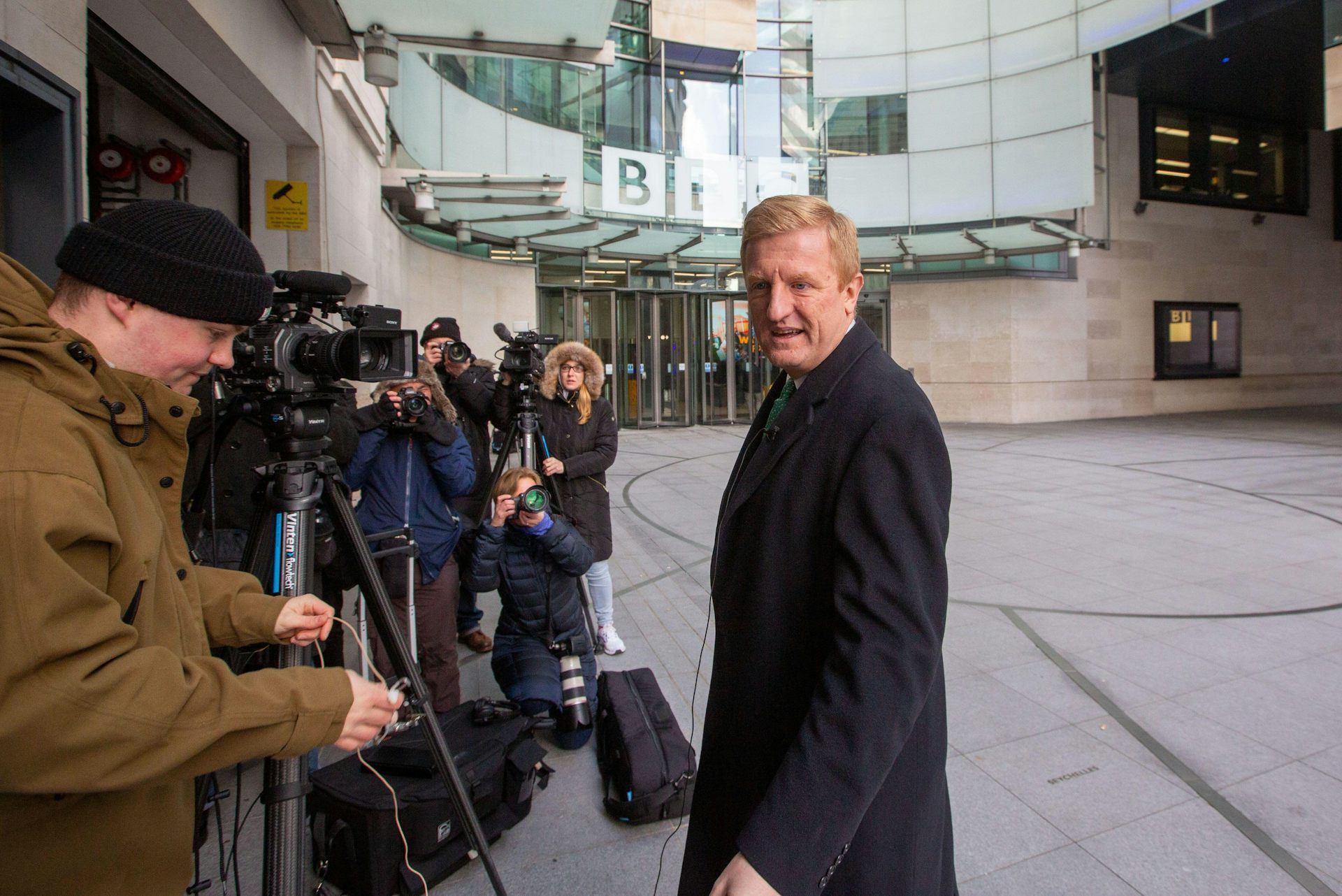 Oliver Dowden standing in front of press photographers outside the BBC in London.