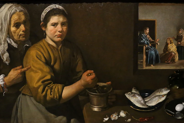 Painting of an older person pointing at a maid grinding garlic; a painting of Christ and Mary hangs above the plates of fish and eggs on the table