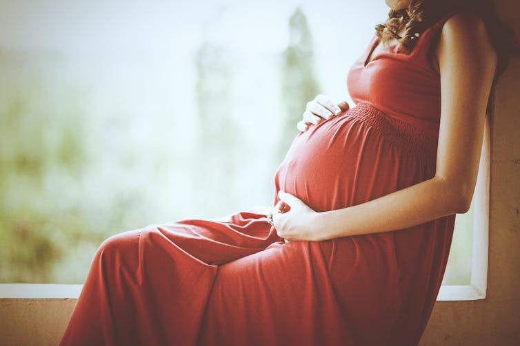 A pregnant woman holding her stomach.