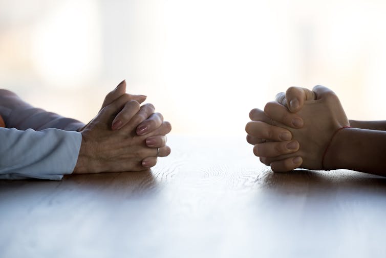 Two clenched hands opposite each other on a table.