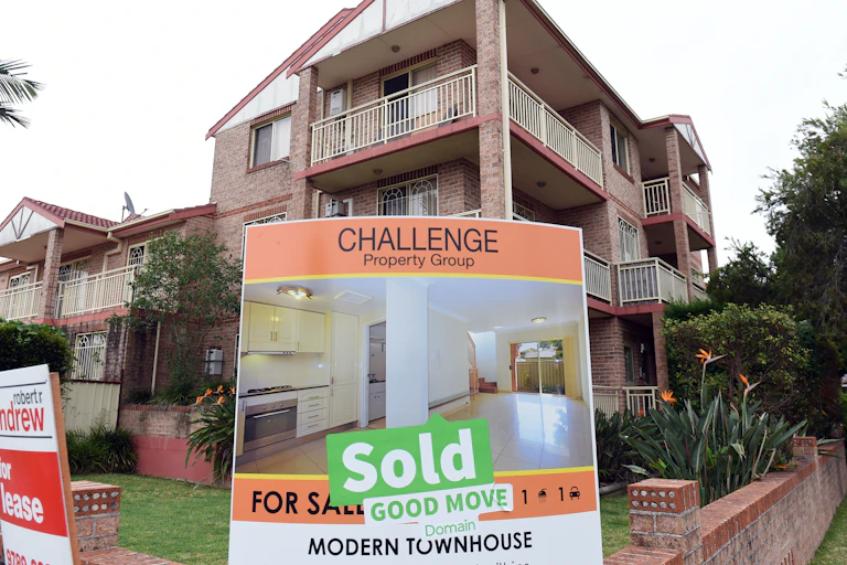 Multi storey block of townhouses with a "Sold'' real estate sign out the front.