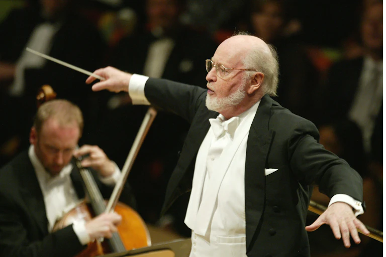 A man in white tie and tails on a podium leads an orchestra