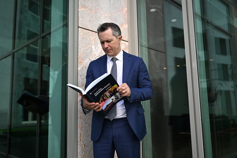 Federal Education Minister Jason Clare stands tine the grounds of Parliament House in Canberra and looks at the Universities Accord final report.