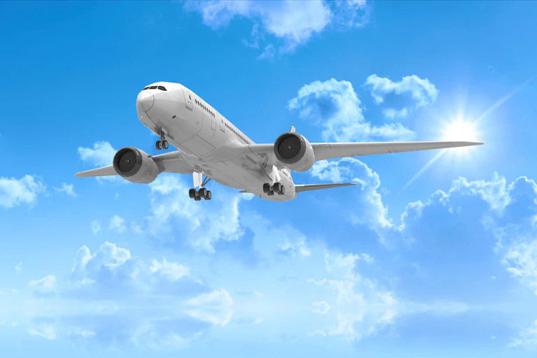 Against a background of blue sky and fluffy clouds, an airplane in flight.