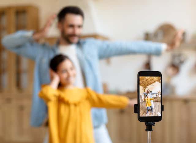 Un père et une fille se filment avec un smartphone